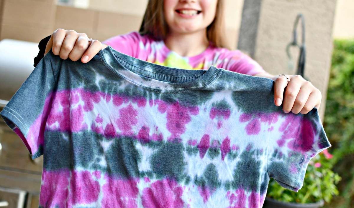 holding up a tye-die shirt