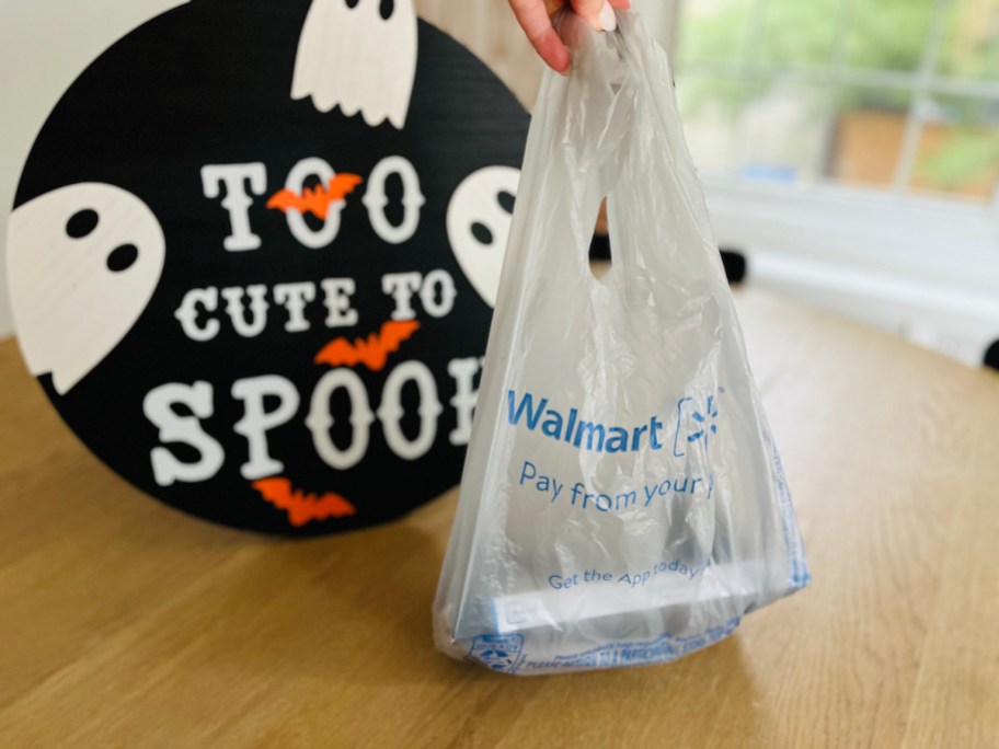 hand holding up walmart bag with halloween too cute to spook sign
