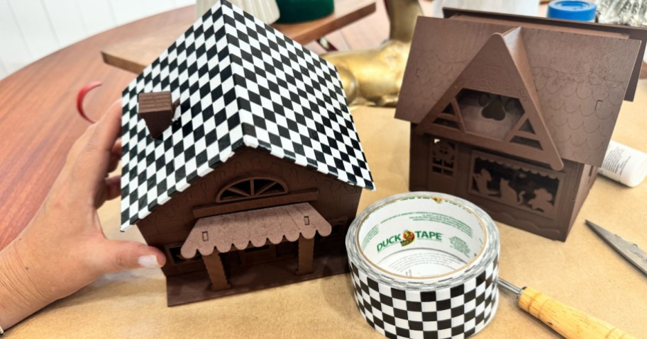 wooden craft houses that have been painted and started to be decorated with black and white duct tape and faux snow and other decor