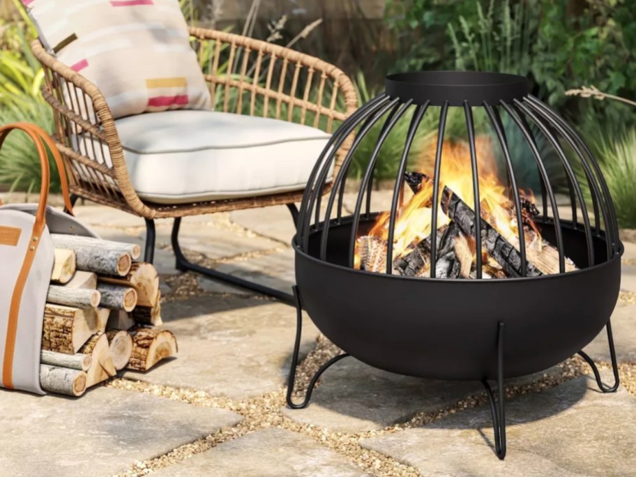 a round black fire pit by a chair on a patio