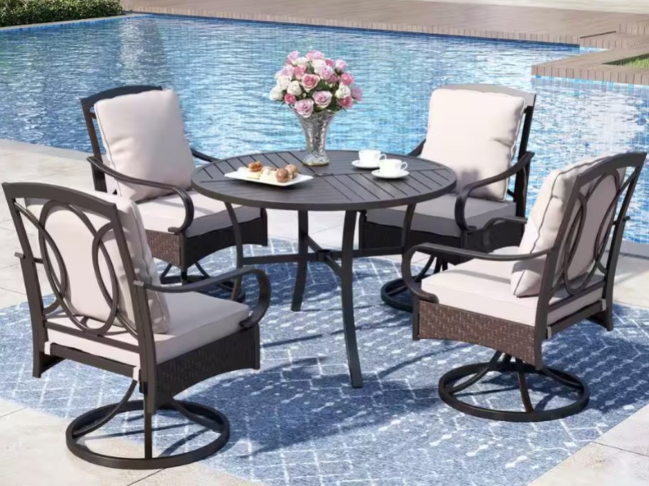 an outdoor dining table set by a swimming pool