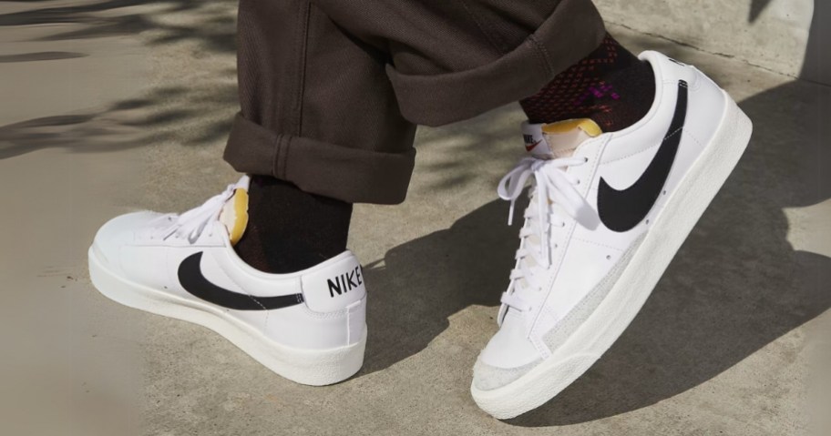 person's feet wearing white with black accents Nike Blazer low shoes