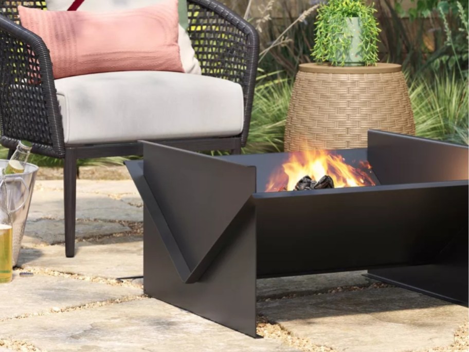 a black fire pit by a chair on a patio