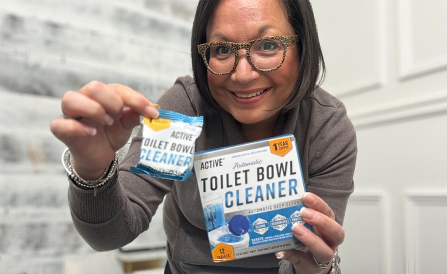 Woman standing in bathroom holding box of ACTIVE toilet bowl cleaner