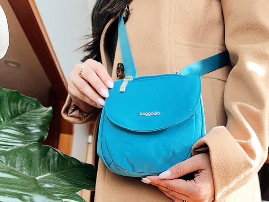 woman in a tan coat with a bright blue crossbody bag