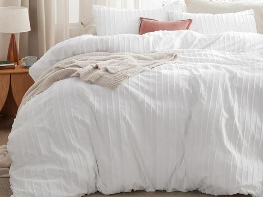A bed with a white duvet covering it 