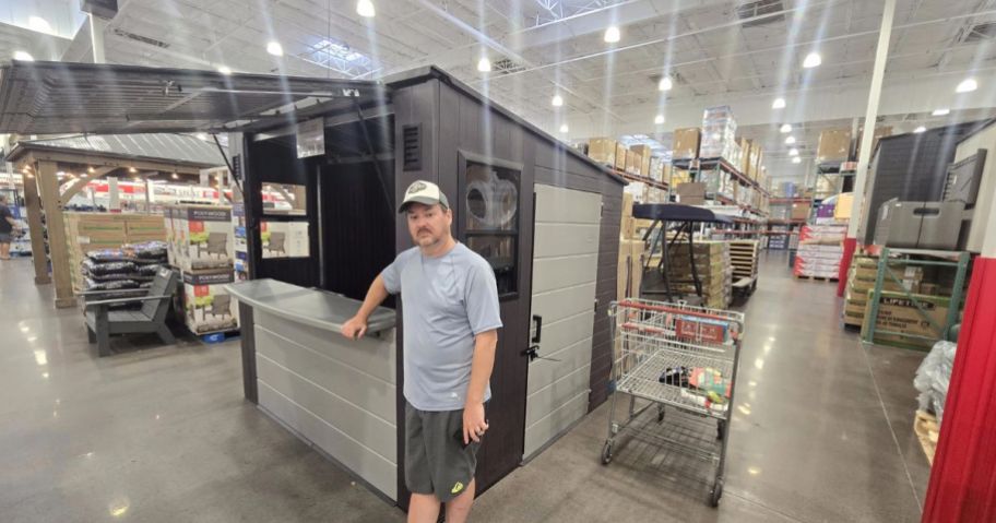 A man standing next to a small entertainment shed in Costco 