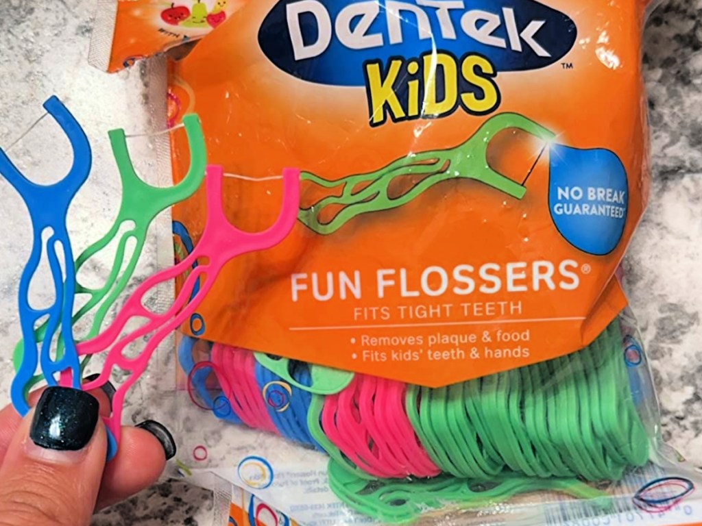 Woman holding up dentek kids flossers in front of bag