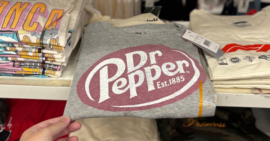 Gray Dr Pepper women’s graphic T-shirt with vintage-style logo, displayed on a Target shelf among other folded tees.