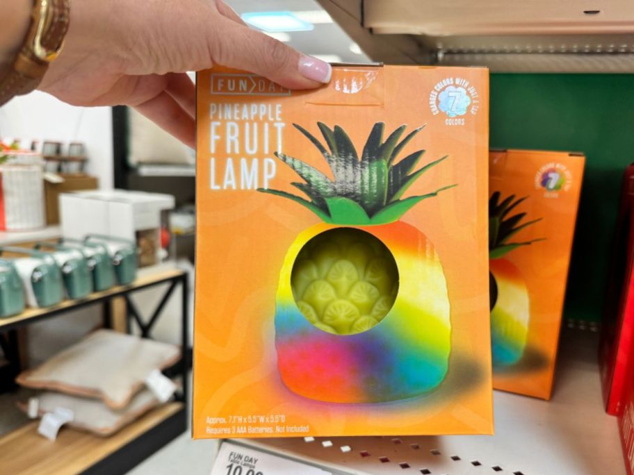 A woman displaying a squishy yellow pineapple lamp at Target