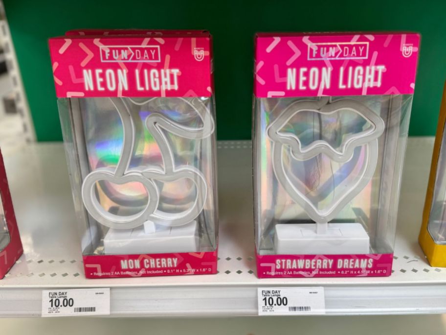 A cherry-shaped and a strawberry-shaped neon light in a box at a store