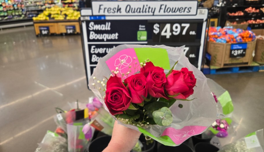 hand holding a bouquet of flower in front of a walmart sign