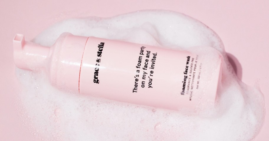 pink bottle of Grace & Stella Foaming Facial Cleanser surrounded by foam
