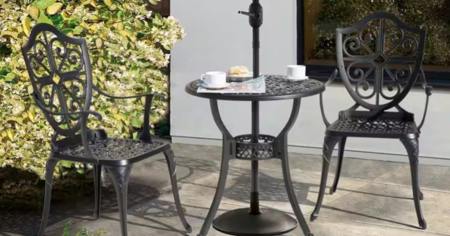 a metal bistro table and chairs set on a patio