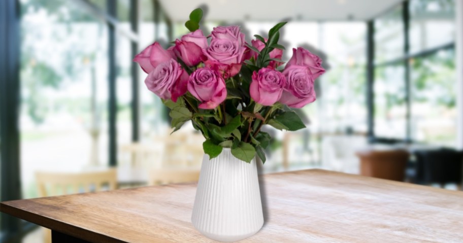 a vase of purple roses on a kitchen table