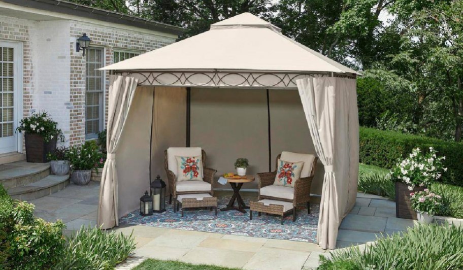 Gazebo with curatins closed with two chairs displayed underneath