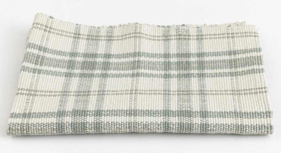 folded sage green and cream plaid doormat rug