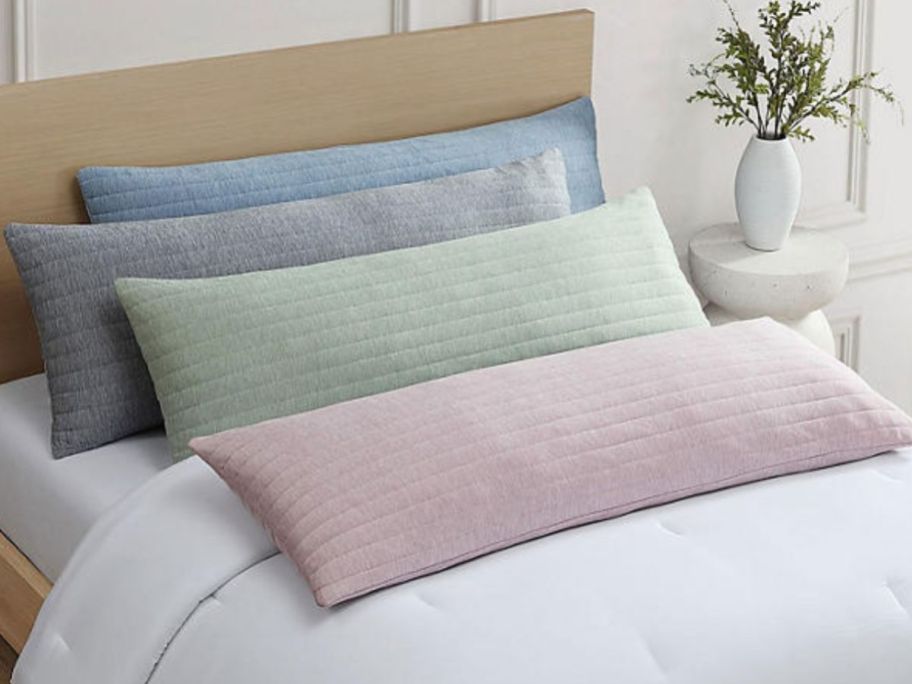 4 Hudson & Main Body Pillows in different clors on a bed