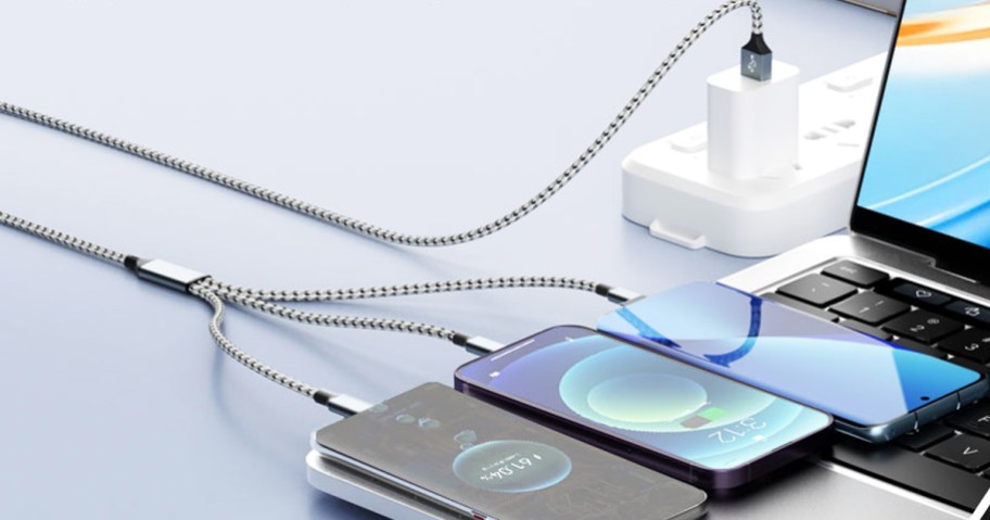 single charging cable charging three phones on top of a laptop