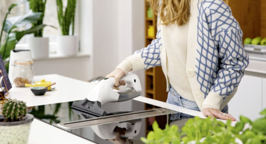woman cleaning her stove with the window vacuum