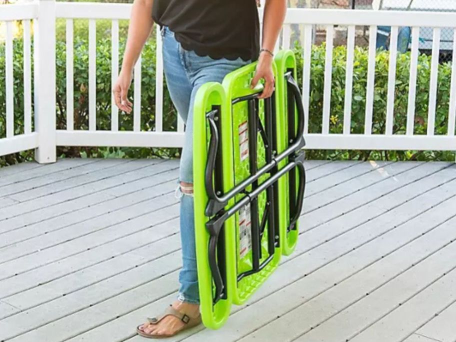 woman carrying a folded Lifetime Children's Picnic Table