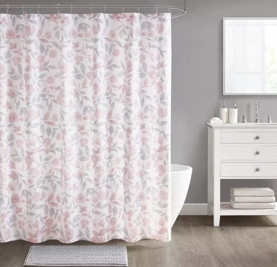 bathroom with a floral print shower curtain, coordinating bath rug, and vanity with lotion and soap pumps