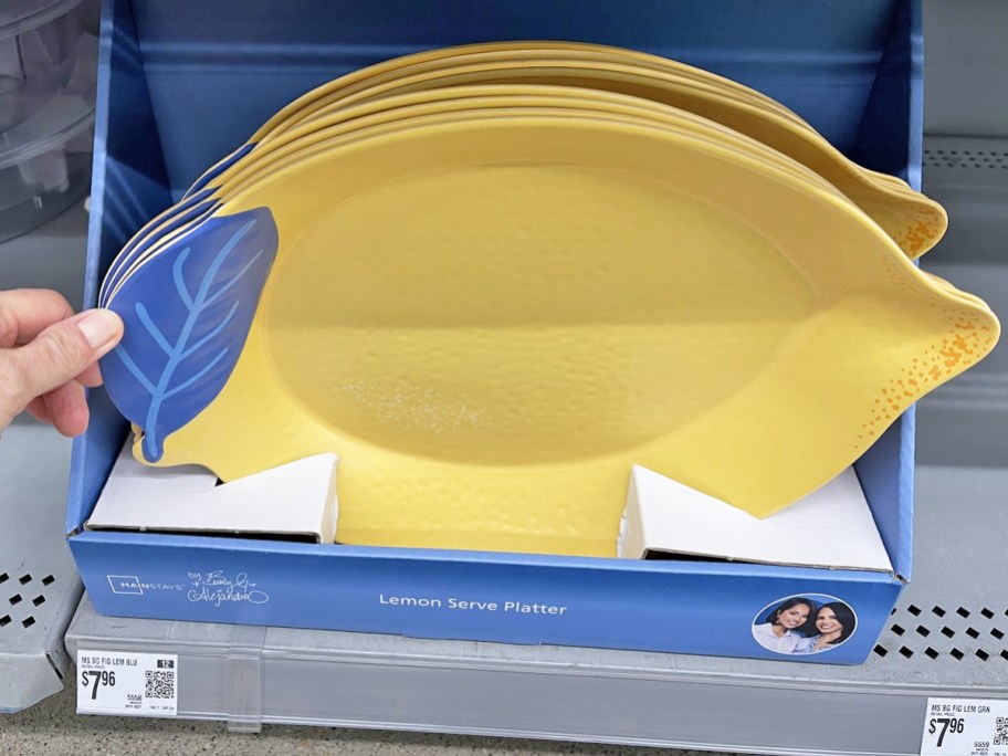 hand touching a display of lemon-shaped serving platters in store