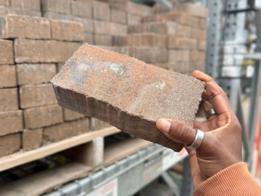 hand holding up a paver stone