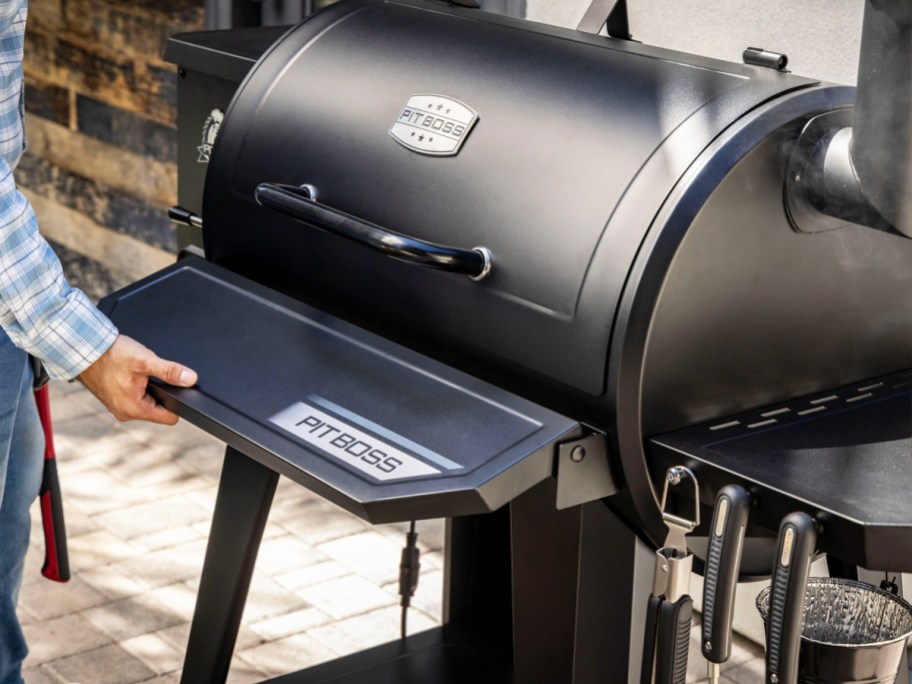 man folding a shelf on black pit boss smoker