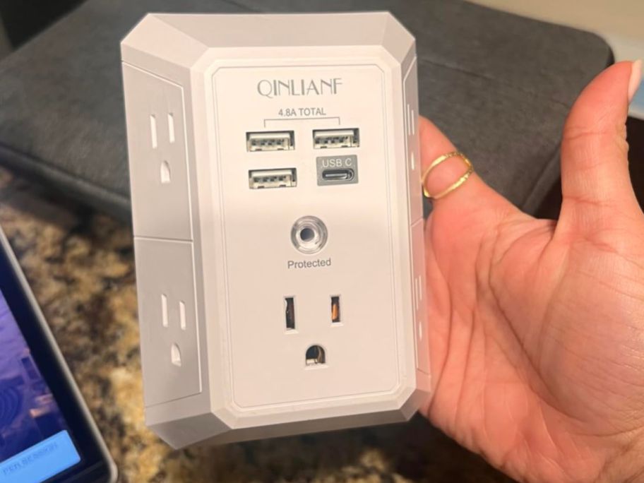 Hand holding a QINLIANF Outlet Extender