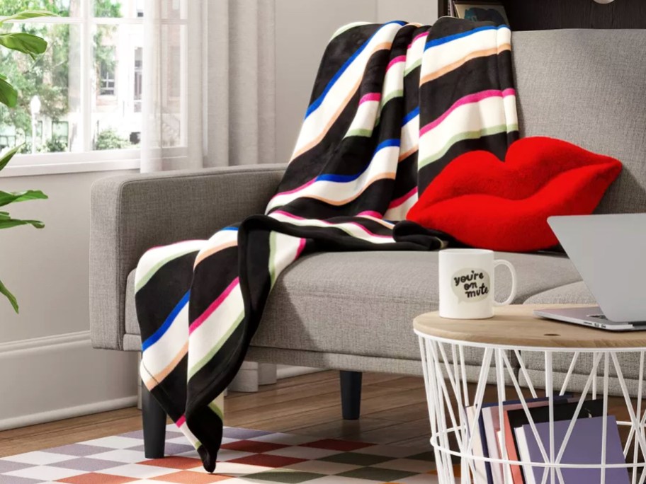 colorful striped throw blanket draped over couch with red lips throw pillow