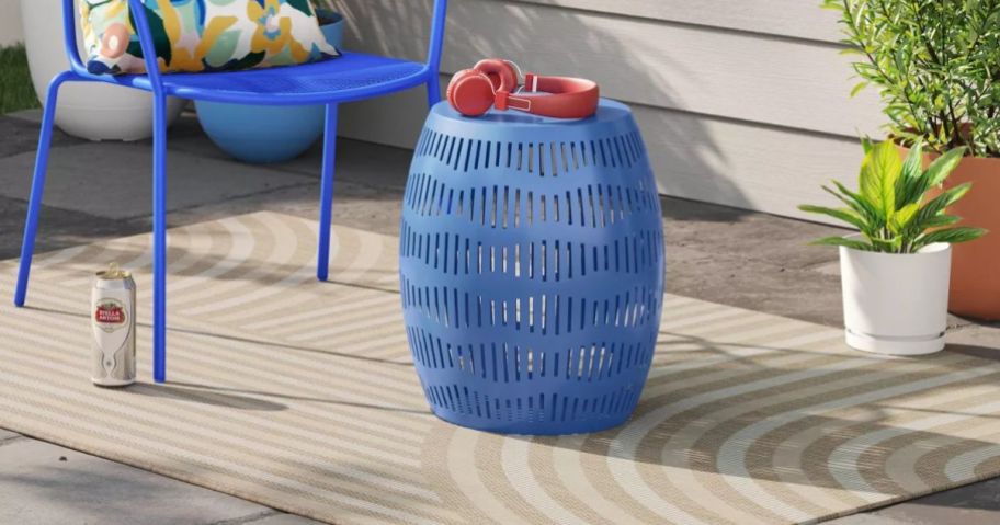 A tan outdoor rug with patio furniture surrounding it