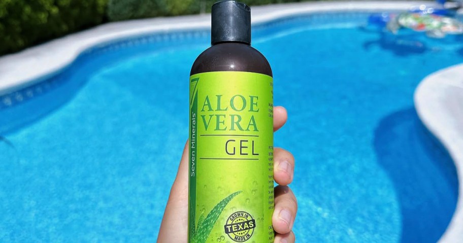 person holding a bottle of aloe vera gel by a swimming pool 