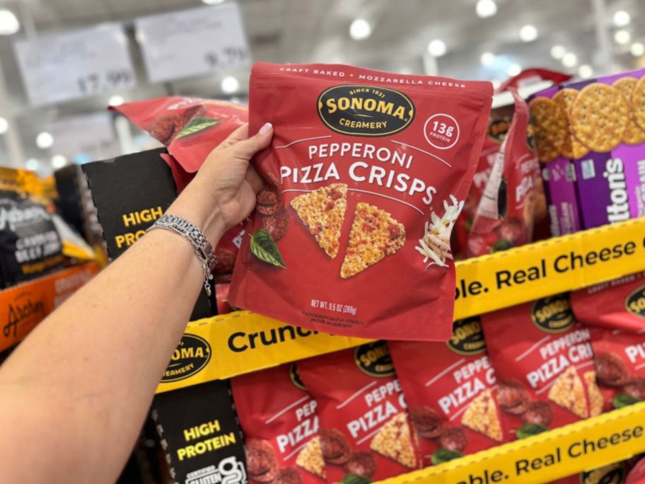 A person holding a bag of pizza crips in a store