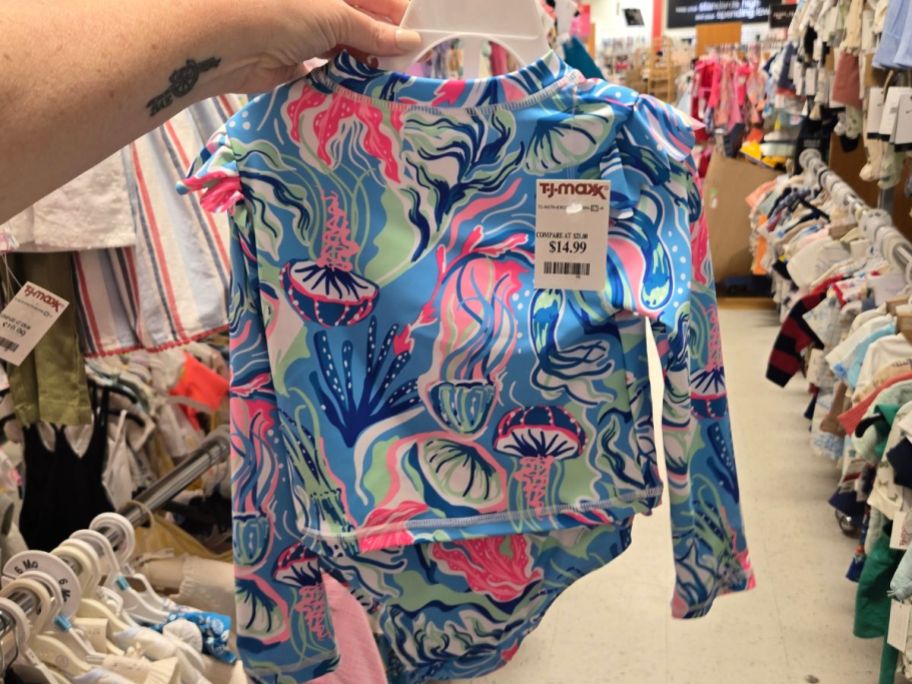 Hand holding a toddler girl's swimsuit at TJ Maxx