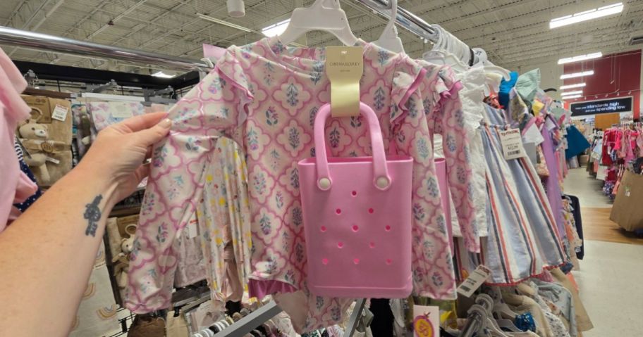 Hand touching the sleeve on a Cynthia Rowley Toddler Swimsuit with a mini Bog Bagg lookalike