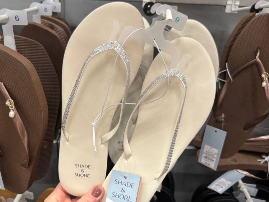 Hand touching a pair of Shade & Shore Women's Cali Flip Flop Sandals with rhinestones on the straps