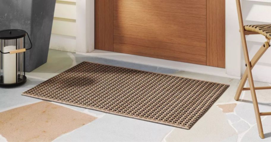 A tan outdoor rug in front of a door 
