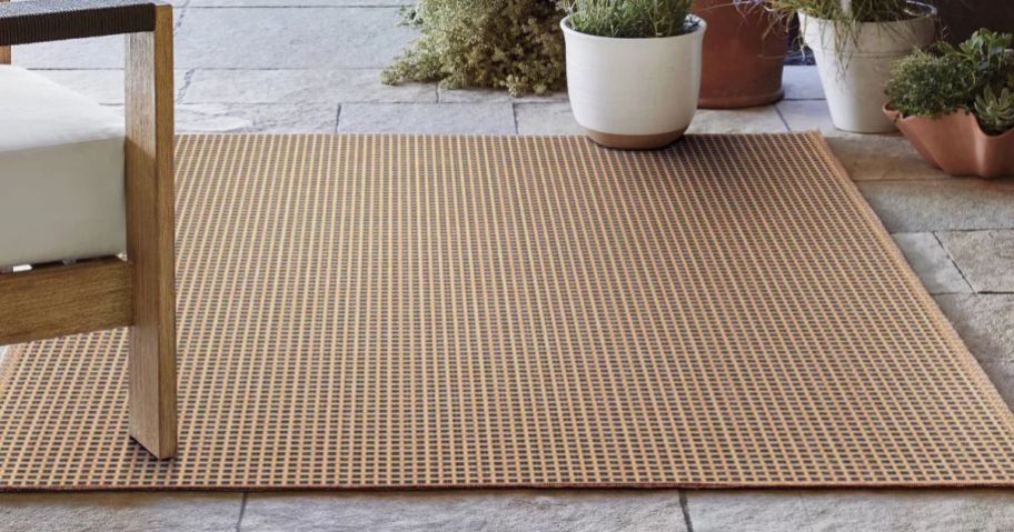 A tan outdoor rug with patio furniture surrounding it
