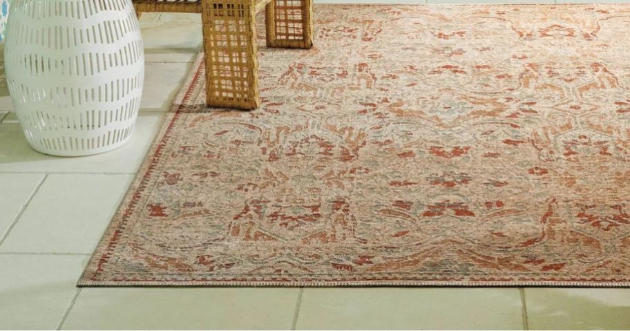 An orange Persian outdoor rug with patio furniture surrounding it