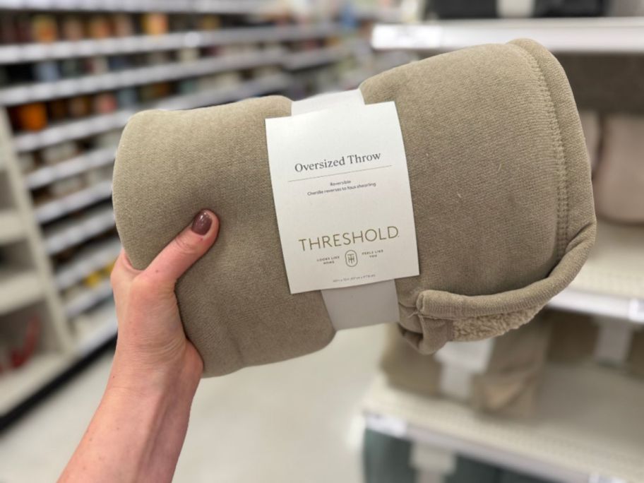 A person holding a tan blanket in a store