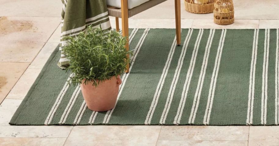 A green and white striped outdoor rug with patio furniture surrounding it