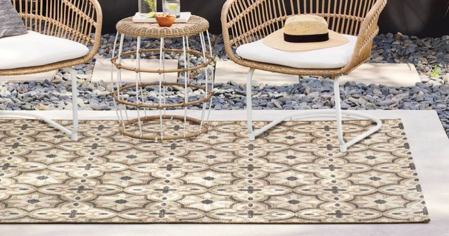 A tan tile-looking outdoor rug with patio furniture surrounding it