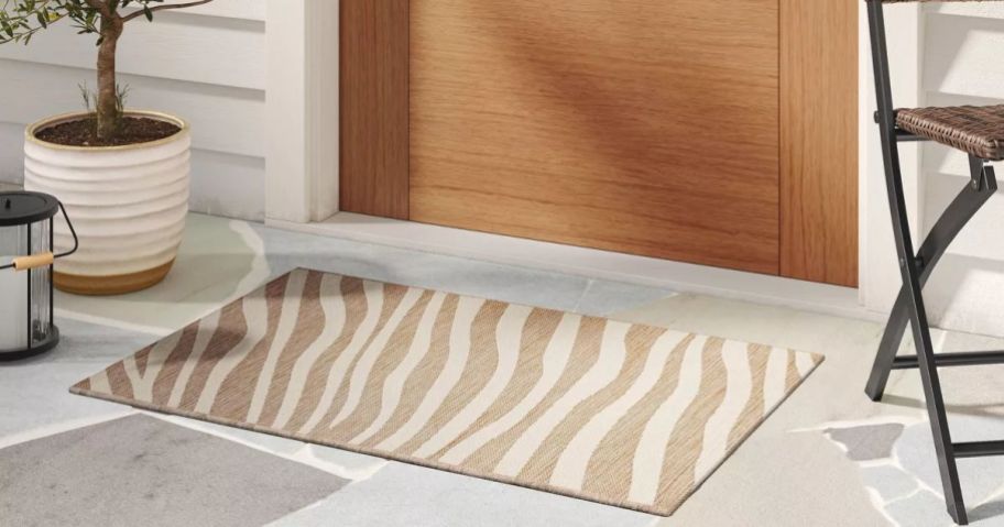A tan and cream wavy-lined outdoor rug in front of a door 