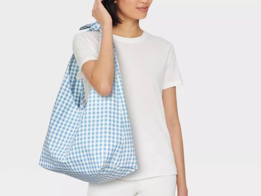 A woman carrying a blue and white Universal Thread Knotted Slouchy Shoulder Tote Bag