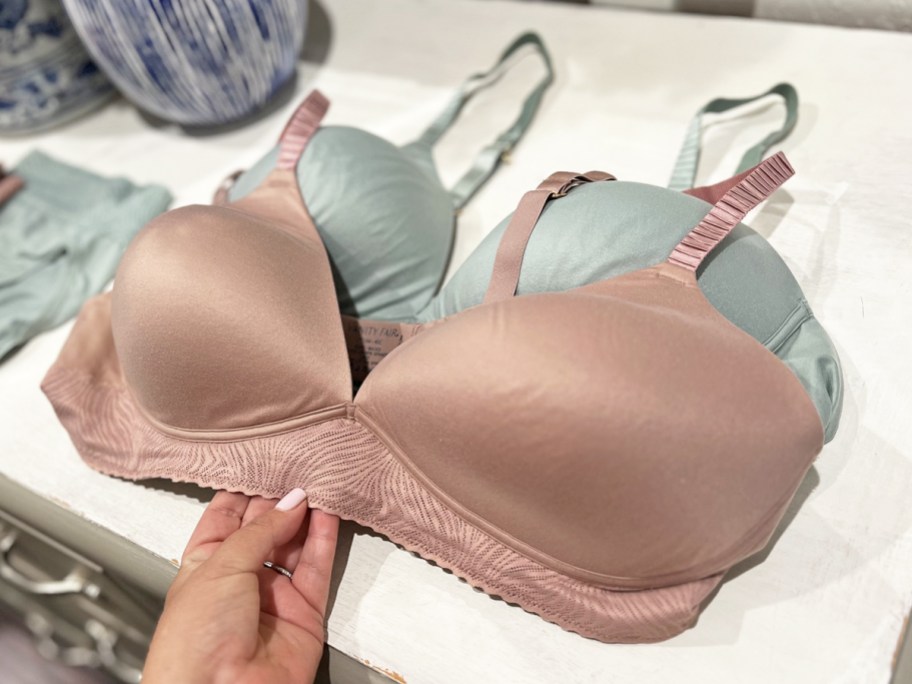 hand touching blush colored bra on top of dresser