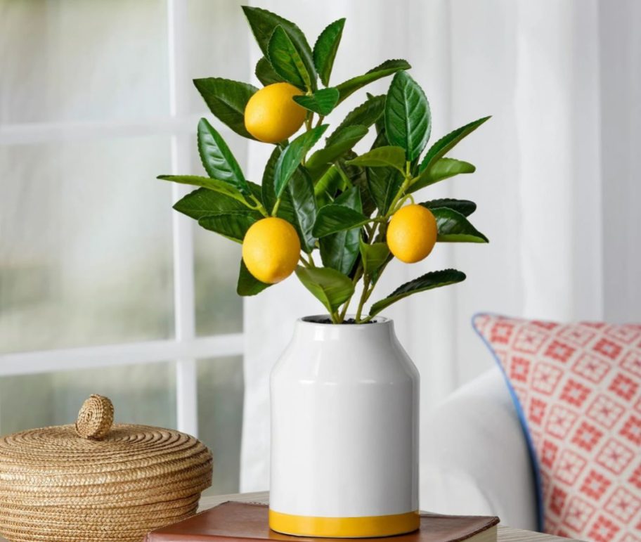 A ceramic vase with a faux lemon tree in it