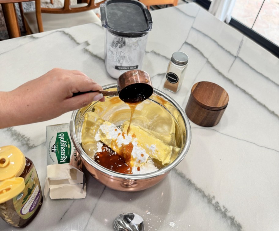 adding honey to mixing bowl to make honey butter 