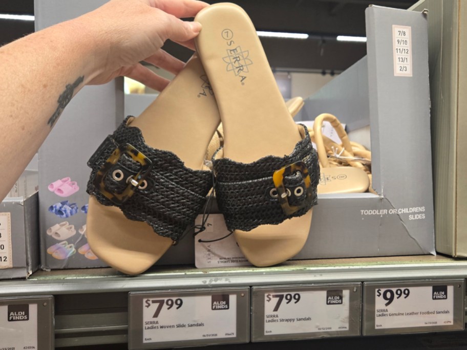 hand holding black and tan sandals