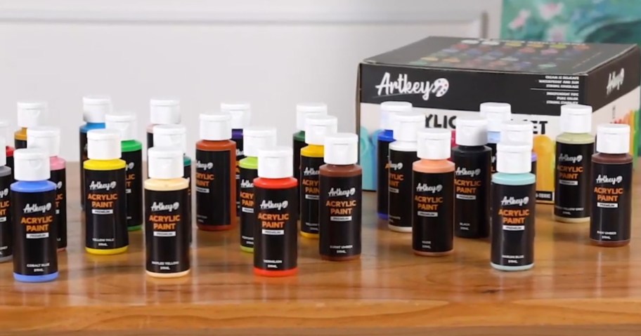 set of acrylic paint in various colors on a table with product box